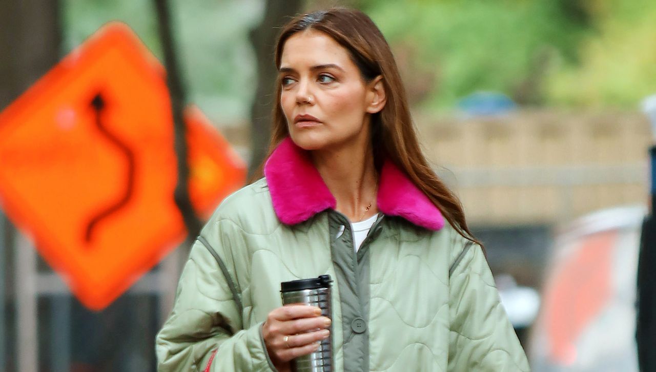 Katie Holmes walking in manhattan wearing a utility coat and drinking coffee