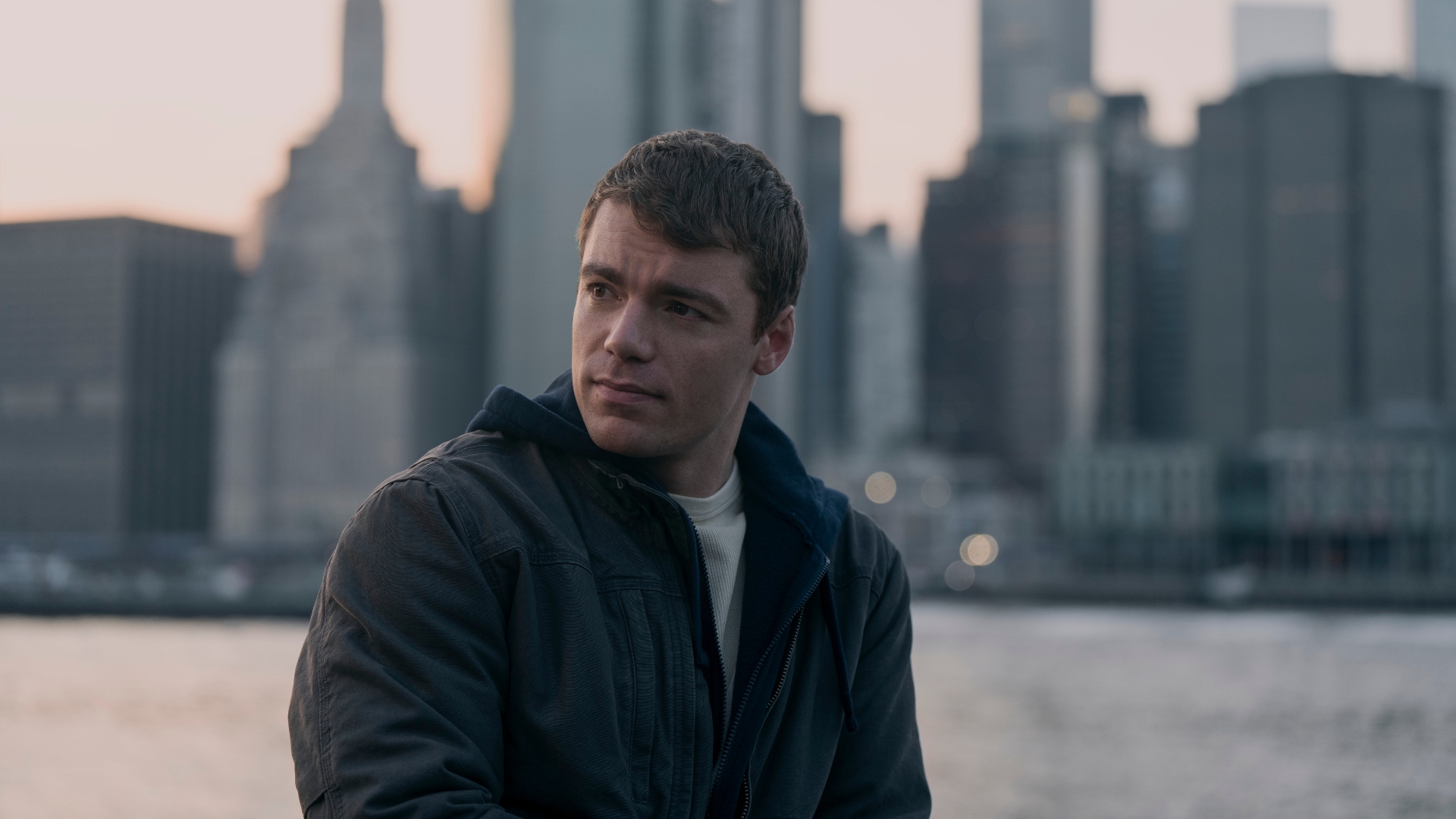 Peter stands in front of a skyline in The Night Agent