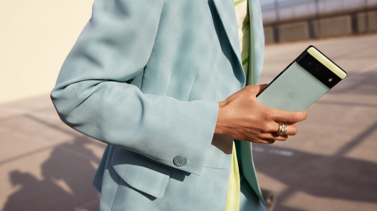 A Pixel 6 in Sorta Seafoam held by someone wearing a matching suit