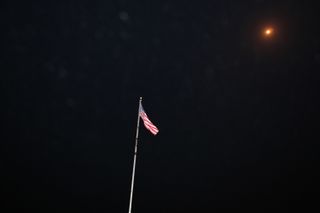 A U.S. flag at NASA's Press Site flies during the liftoff from American soil of the Falcon 9 rocket and Dragon capsule from Space Launch Complex 40 on Cape Canaveral Air Force Station in Florida on Sept. 21, 2014. The rocket launched SpaceX's fourth unman