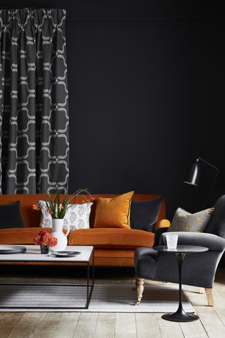 Black living room with orange velvet sofa