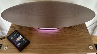 The Bowers & Wilkins Zeppelin Pro Edition on a shelf with a pink light on next to a music player.