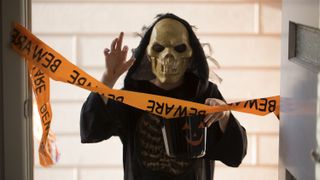 Kid dressed up in reaper costume behind caution tape