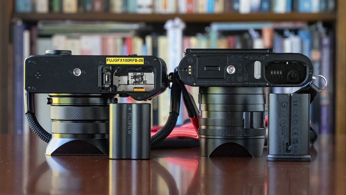 Fujifilm GFX100 RF alongside Leica Q3, underside of each camera with battery