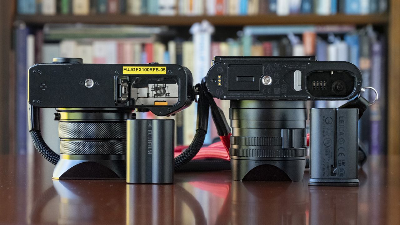 Fujifilm GFX100 RF alongside Leica Q3, underside of each camera with battery