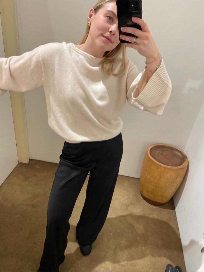 Florrie wears a cream knit, black satin trousers and loafers