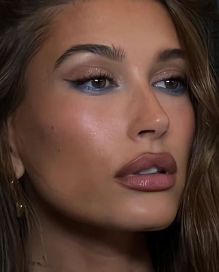 A photo of Hailey Bieber wearing cobalt blue eyeliner along her lower lashes.