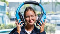 A comically huge set of blue headphones, being held on either side of a model's head