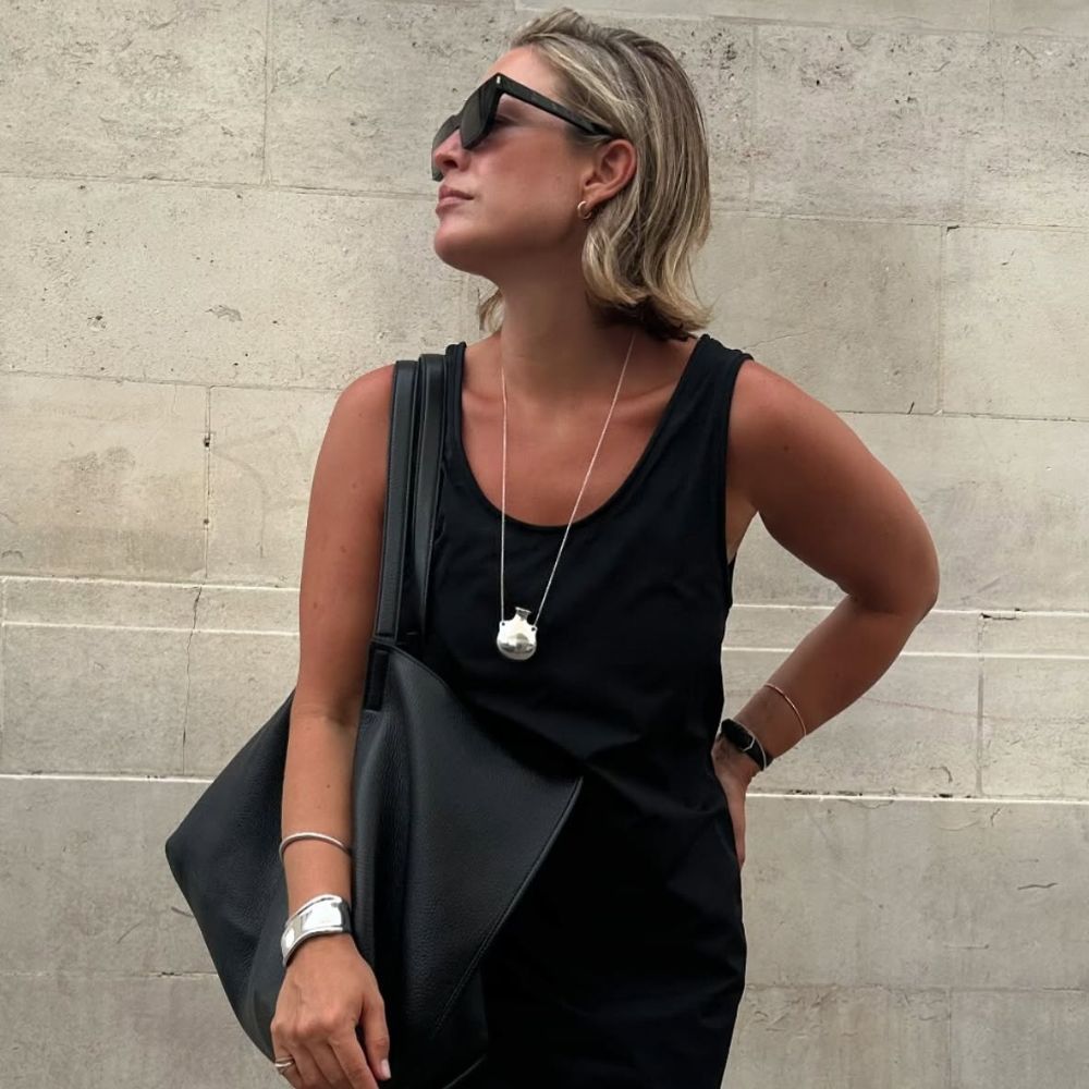 A woman standing outside in a black dress with a linen blonde bob hairstyle