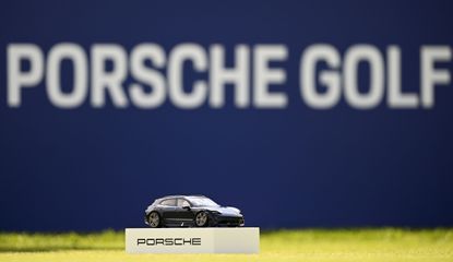 A Porsche car tee box in front of a Porsche advert board