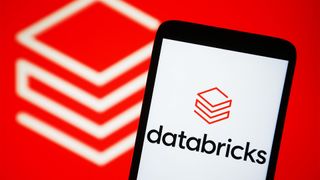 Databricks logo pictured on a smartphone with branding pictured on red blurry background.