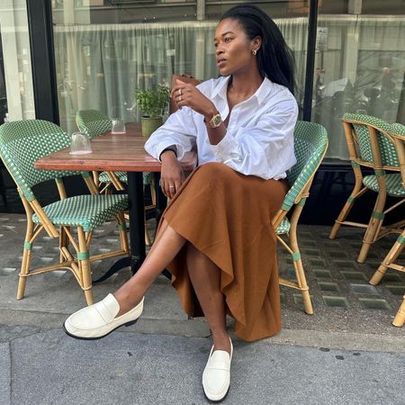 British fashion influencer Marilyn Nwawulor-Kazemaks wearing a chic outfit with a camel color skirt
