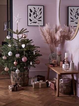 Small Christmas tree with pink decor in a pink hallway