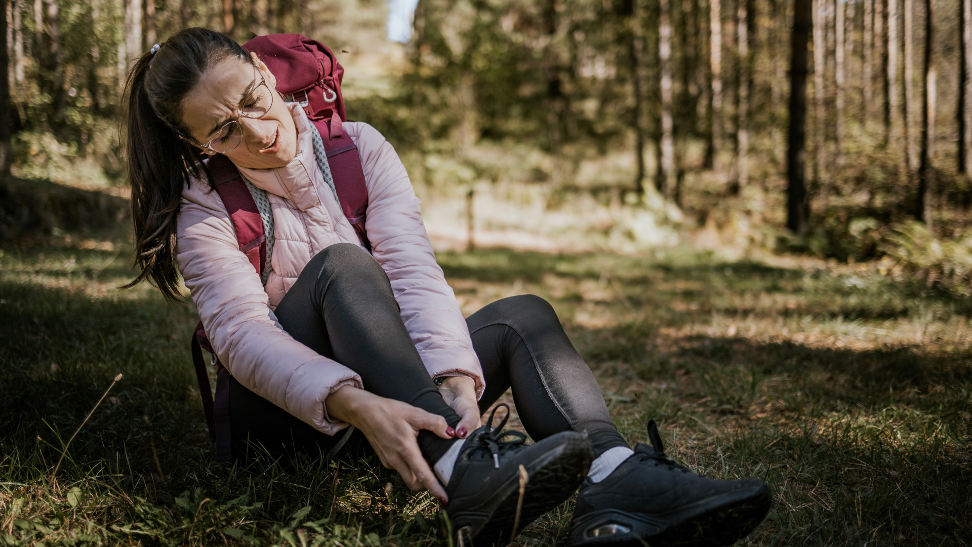 A woman grabbing her ankle in pain whilst out on a hike