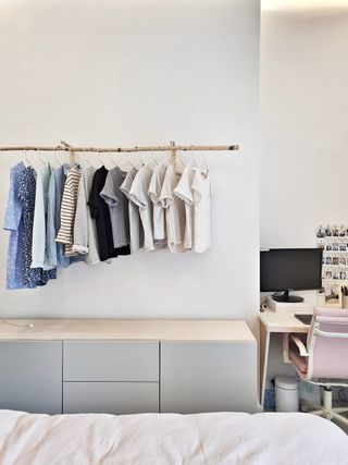 Clothing hanging on a wooden wall-mounted bar in a bedroom