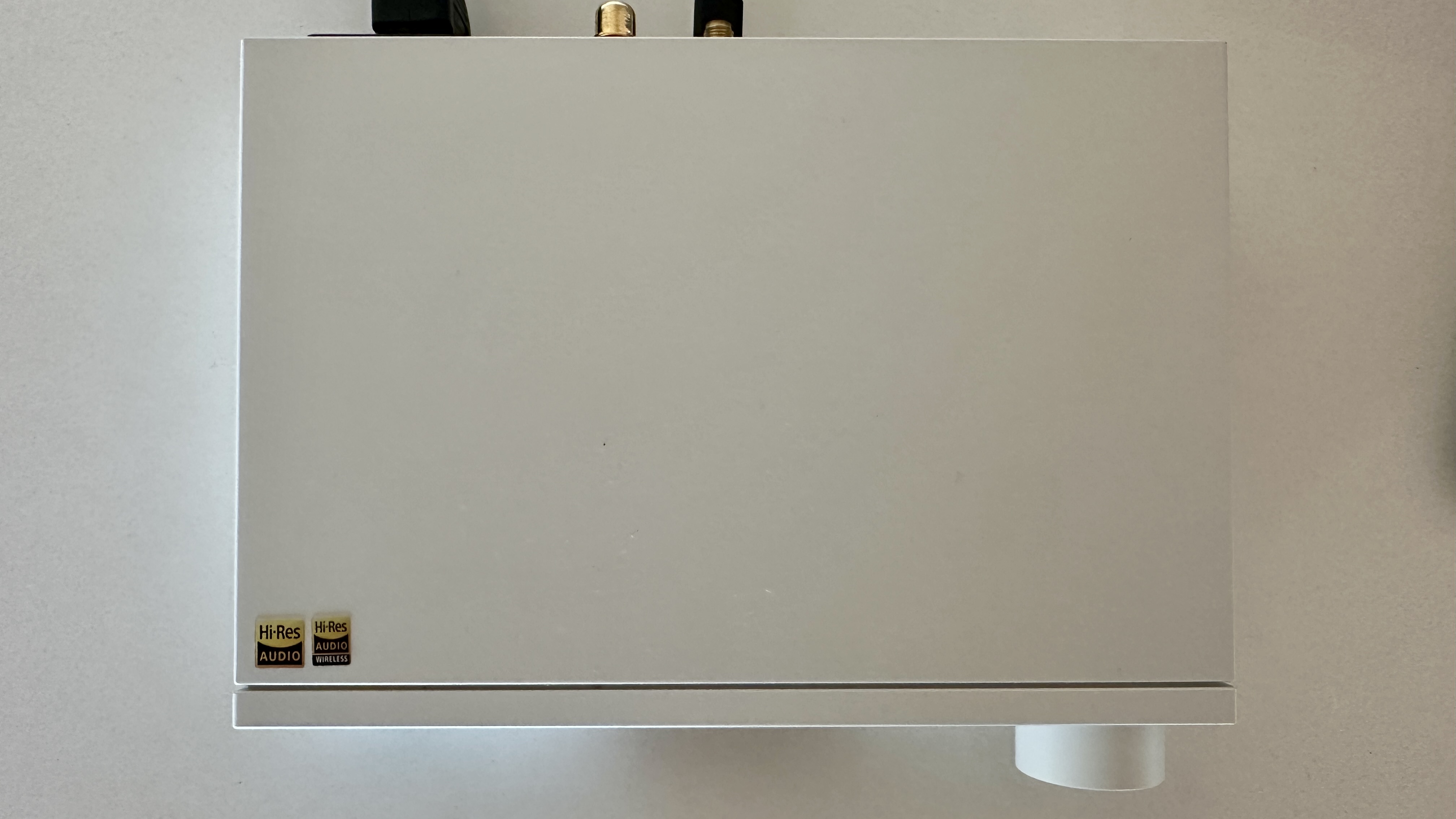 The Topping DX5 II on a light-wood table, showing the VU meter, ports and just-seen remote