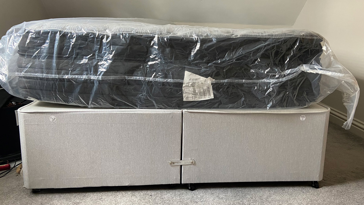 The Zoma Boost mattress on a bed, wrapped in plastic