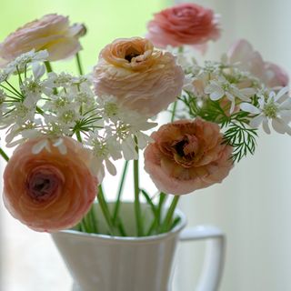 A peachy flower bouquet displayed in a white jug