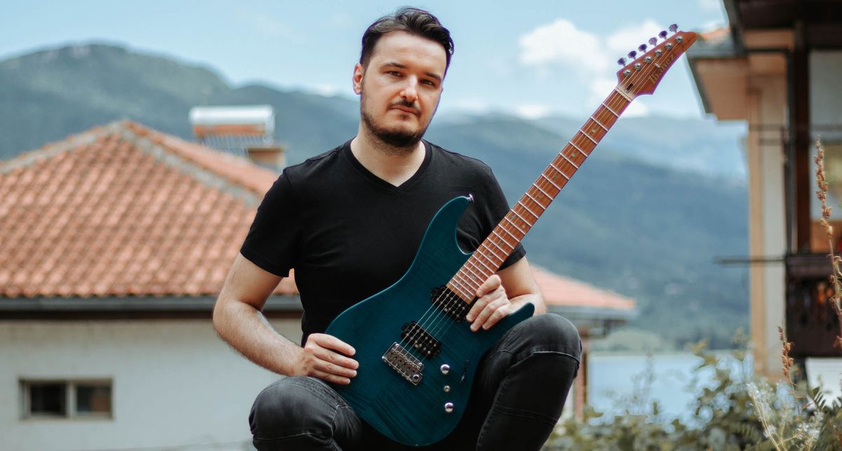 A portrait of Martin Miller with his signature Ibanez, a village in the background