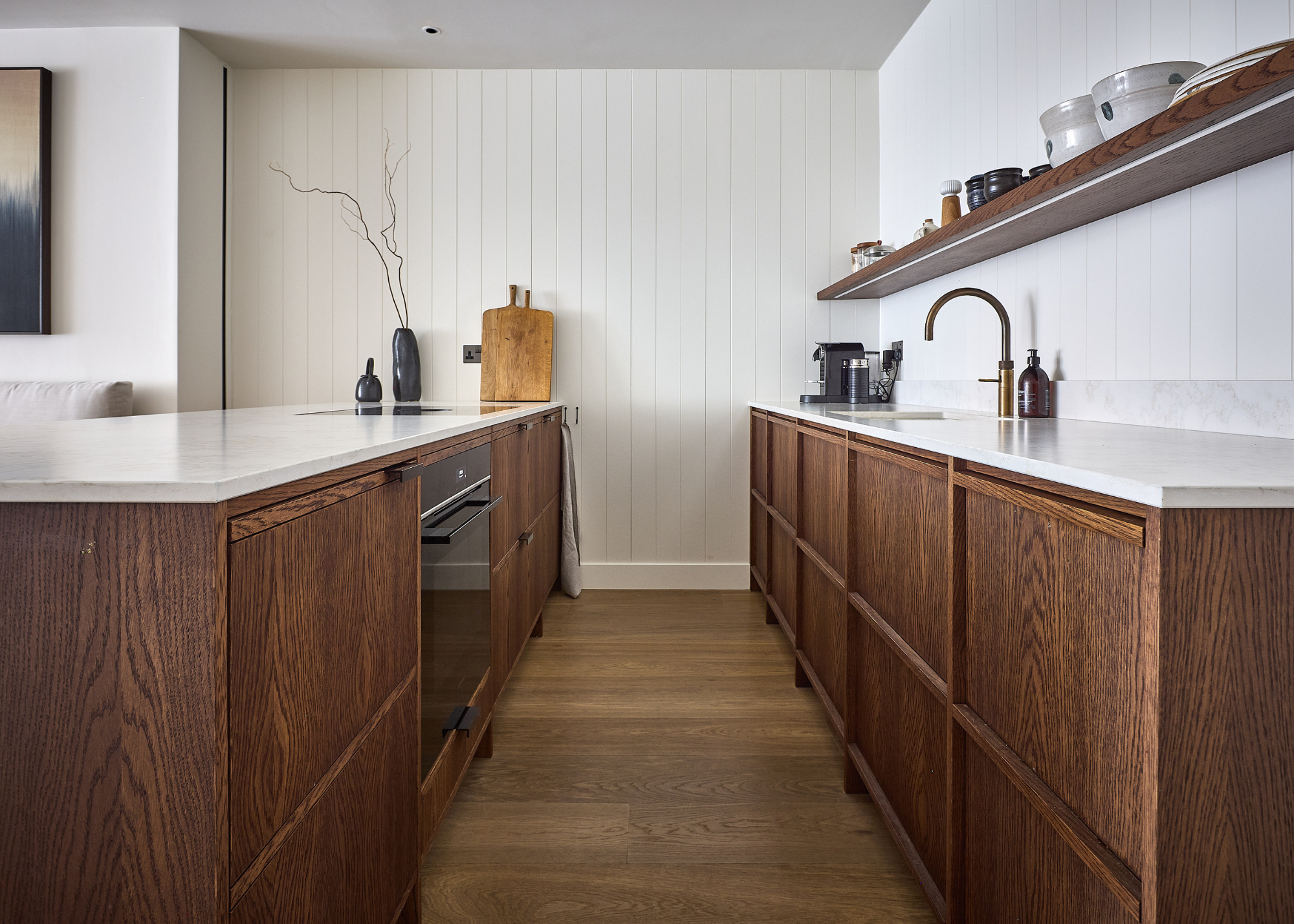a dark wooden kitchen with white counters and a white slatted wood wall