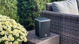 PR shot of the Lodge Powered speaker paced on table outside next to an outdoor sofa