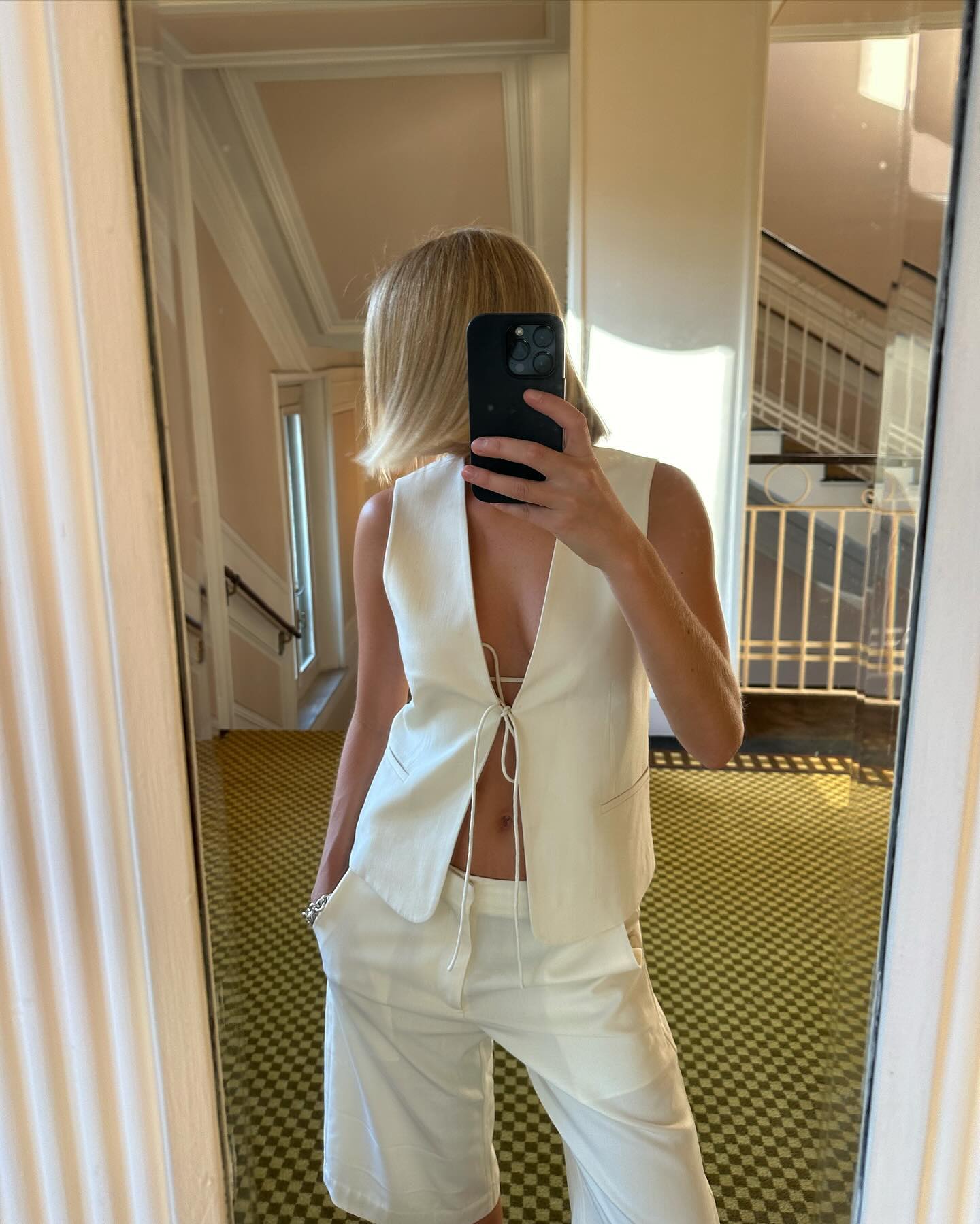 An image of @felicity.alice.brand wearing a white vest and tailored shorts from sustainable fashion brand St. Agni.