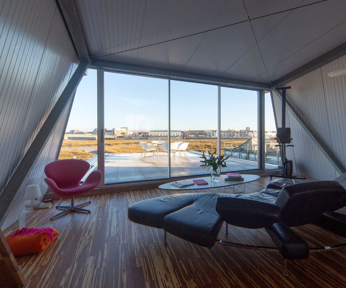 A living area with a glass wall overlooking a balcony and beach