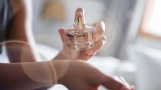 A woman spraying perfume on her wrist to illustrate winter perfume layering
