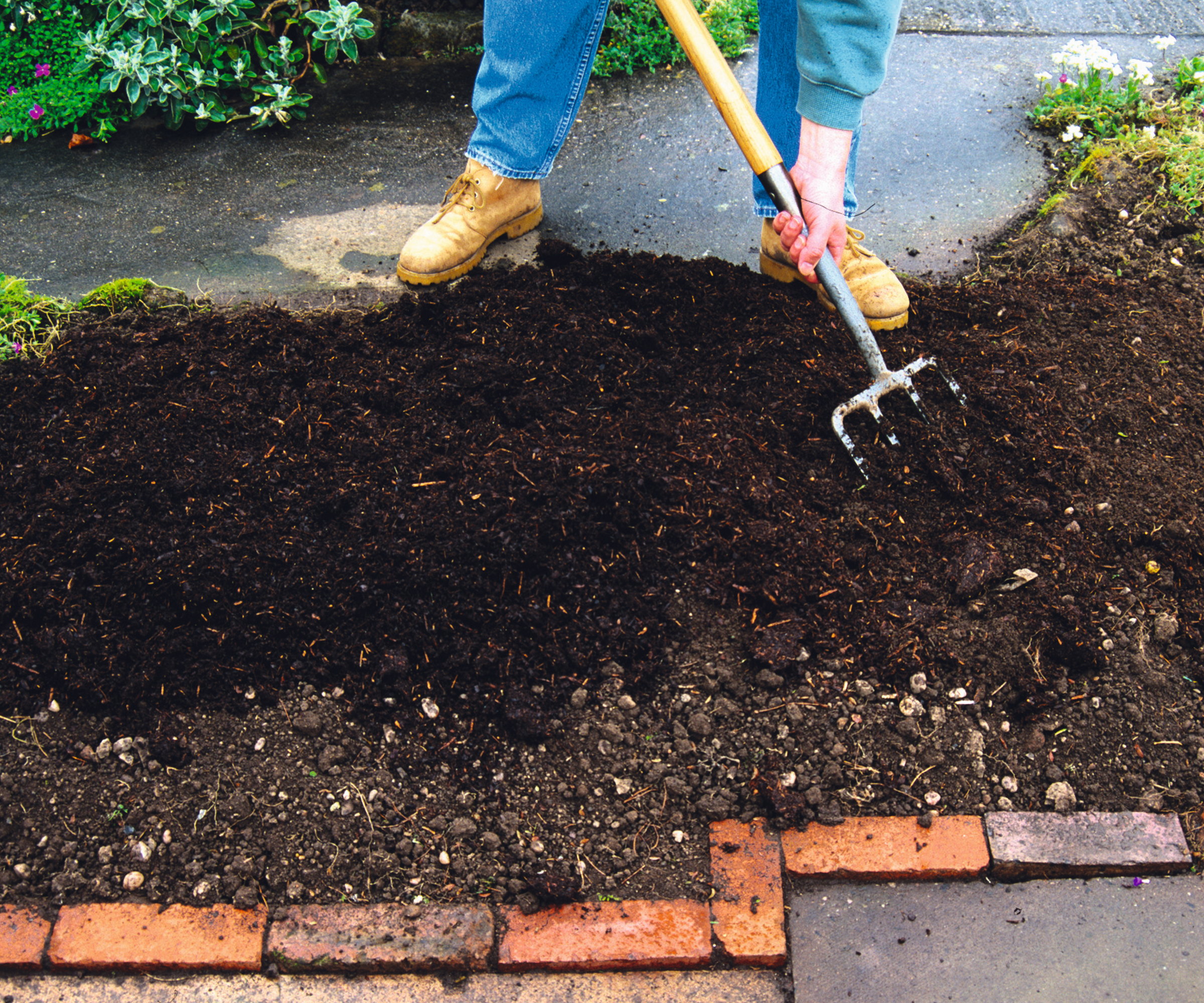 Adding compost to a garden bed with a fork