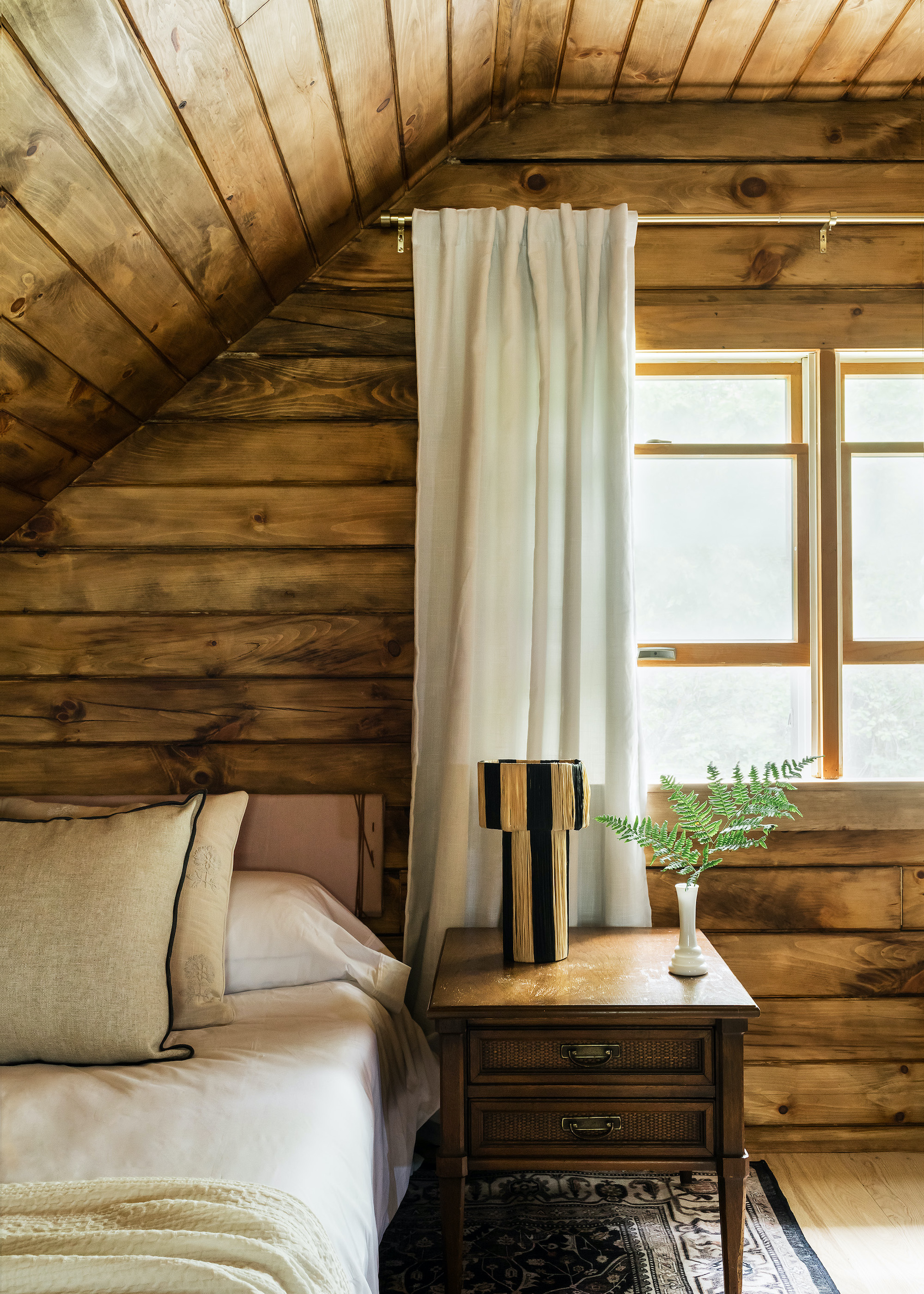 loft conversion with wood clad walls and ceiling, bed and bedside table