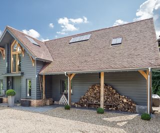 A large oak frame property with an overhanging roof with log storage underneath