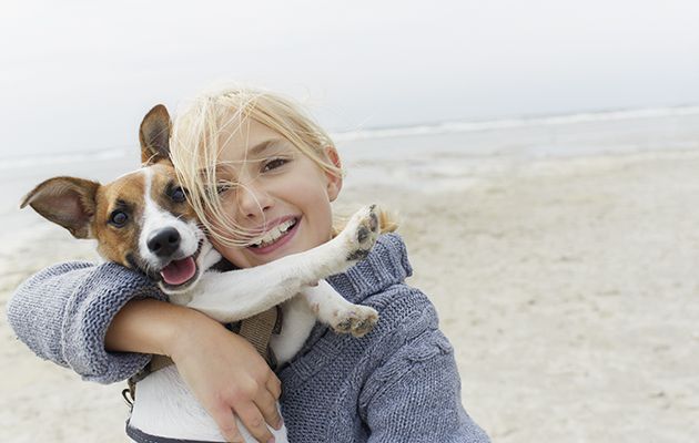 Happy girl hugging dog on the beach, portrait