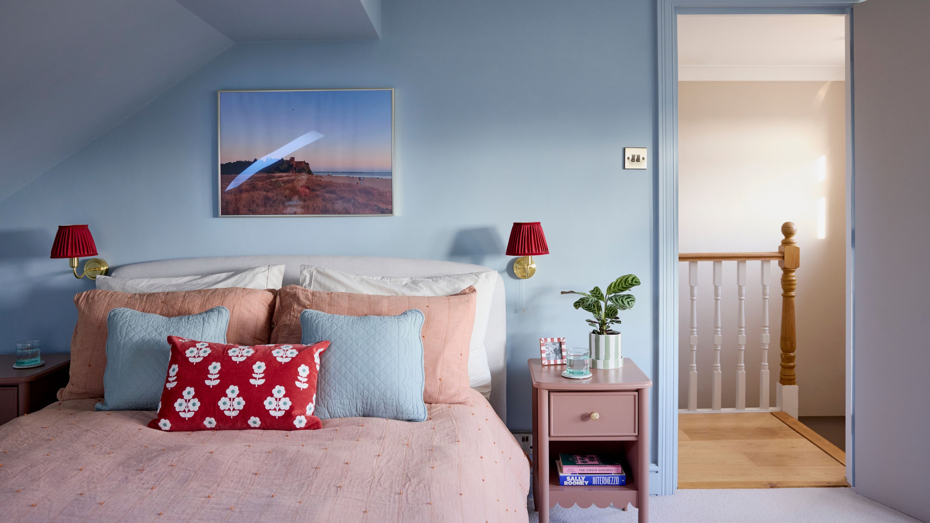 Blue painted bedroom with pink bedding and blue scatter cushions