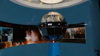 a spherical satellite hangs in a museum