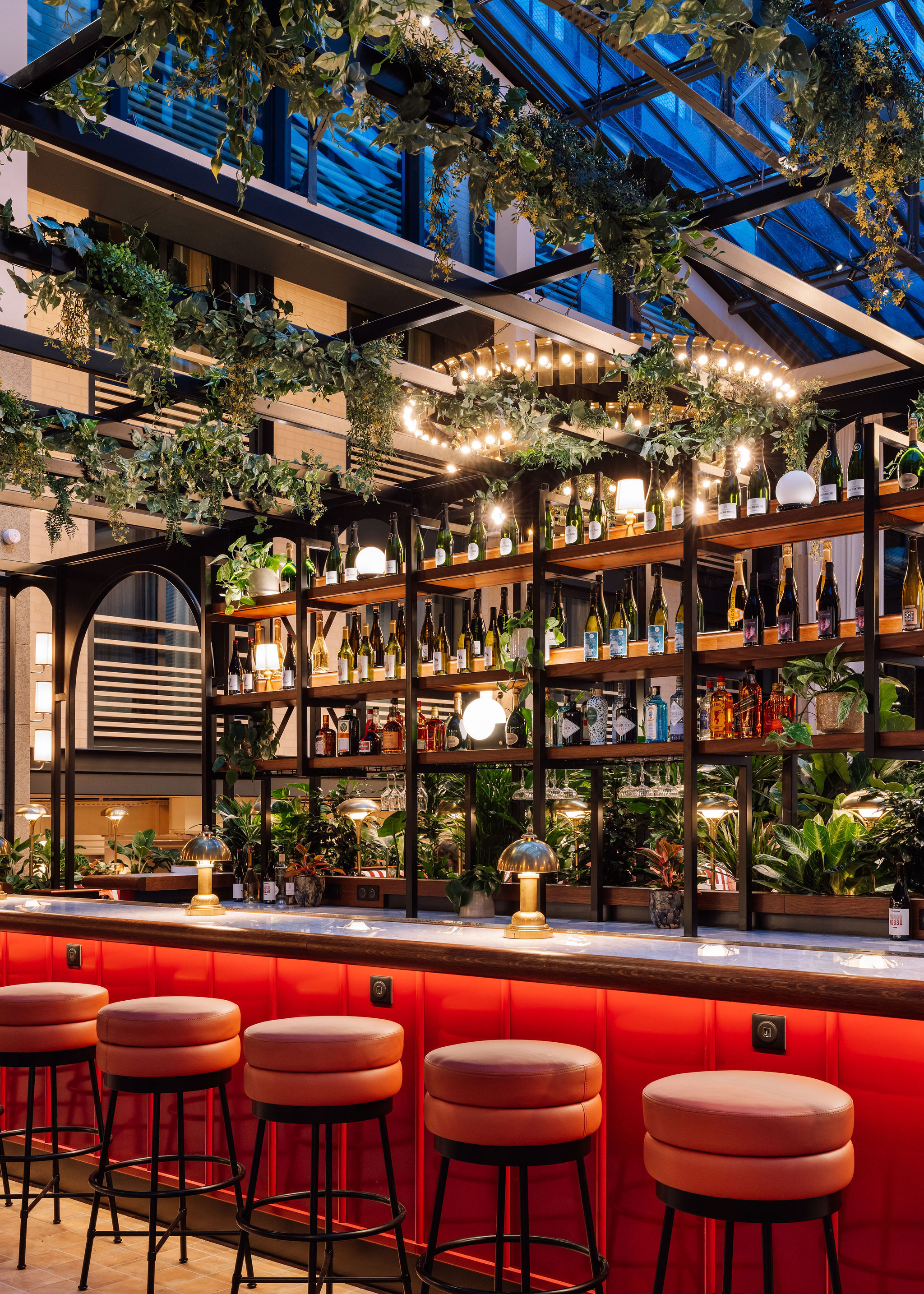 A Parisian hotel's exterior features an ornate, engraved surface painted in buttery and green tones, while inside, trailing plants and Art Deco furniture set the tone.