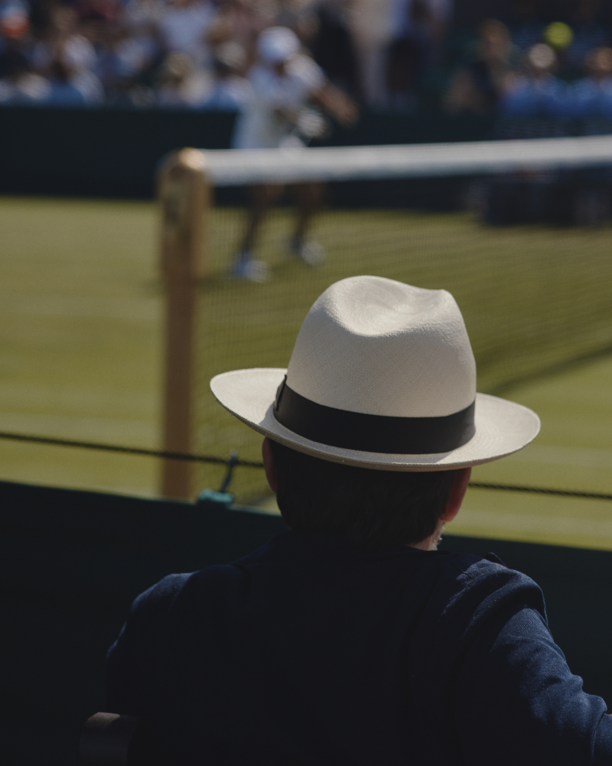 Man in hat from behind, watching tennis at Wimbledon