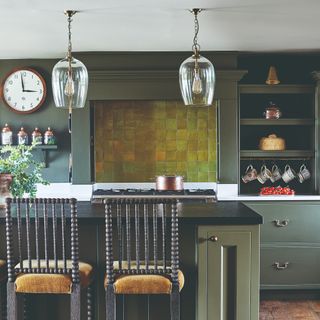 Forest green kitchen with glass pendant lights above breakfast bar