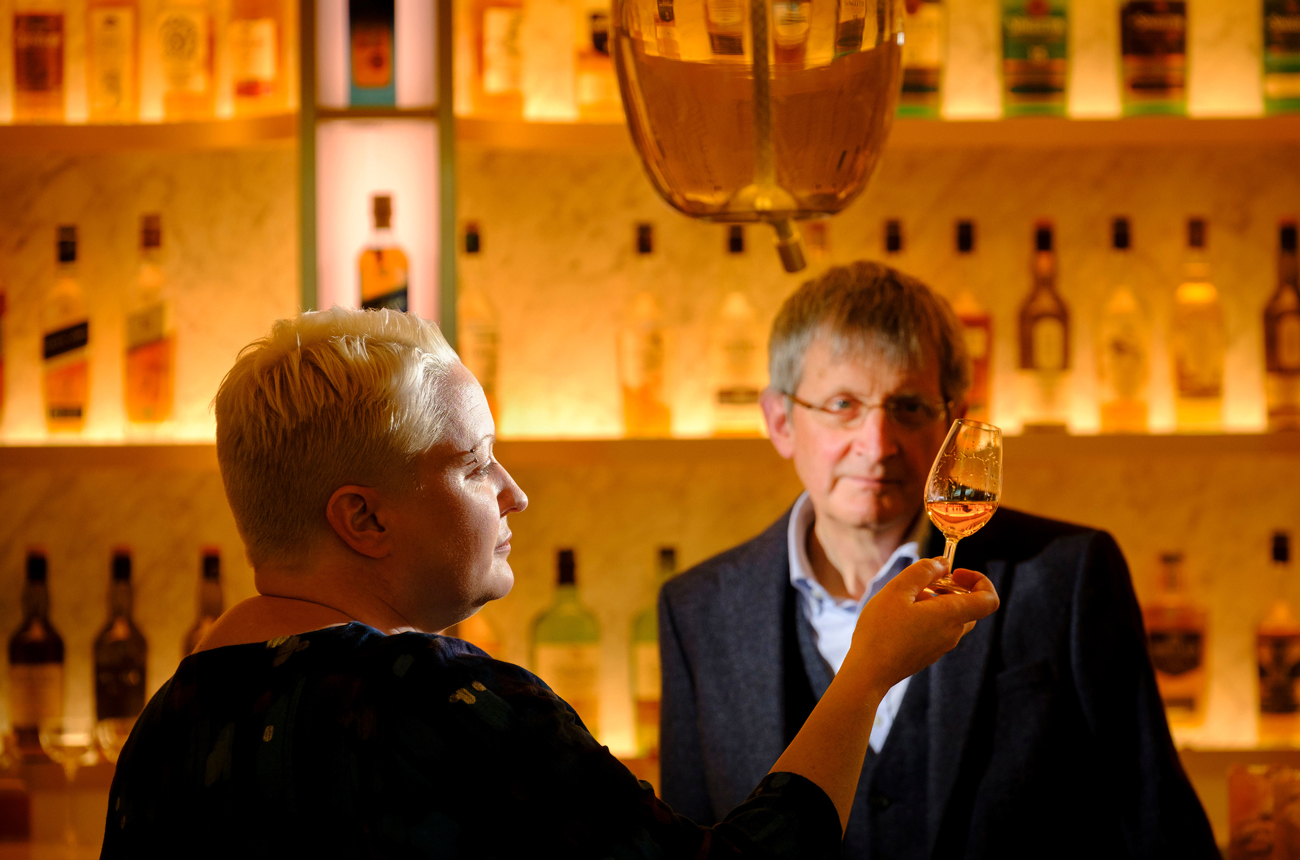 Emma Walker and Jim Beveridge standing in front of a whisky bar