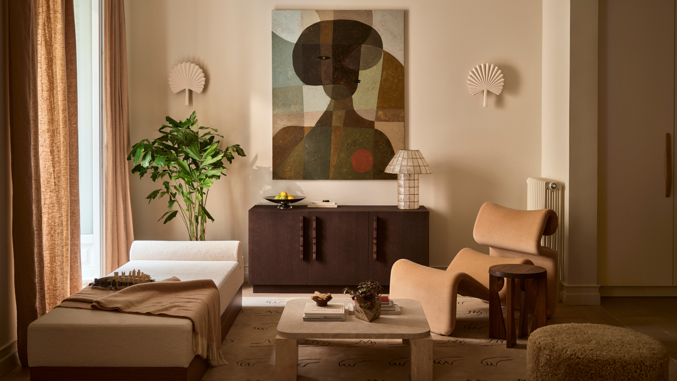 Living room with warm white walls, a mix of cream boucle and wood curved furniture, abstract figurative wall art, cream fan sconces and a neutral rug