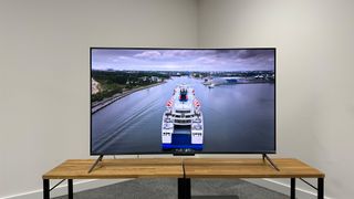 Amazon Fire TV Omni QLED on a wooden stand with an image featuring a large boat on the screen
