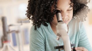 Best microscopes for kids 2021 - Girl looking into a microscope.