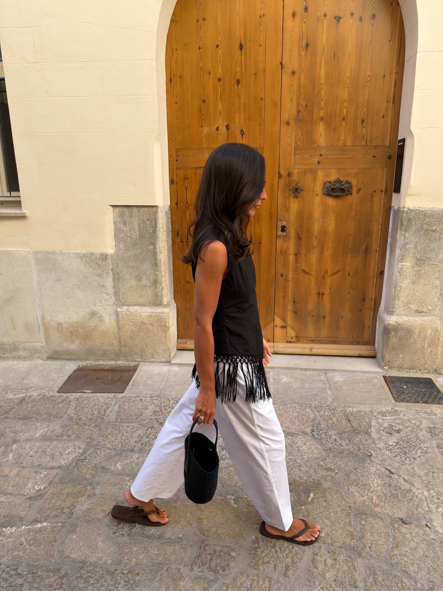 Woman in black fringe top and white pants