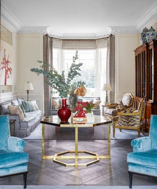 neutral living room with gilded, patterned chairs, gray sofa and blue armchairs in Edwardian house in West London designed by Philip Vergeylen of Nicholas Haslam
