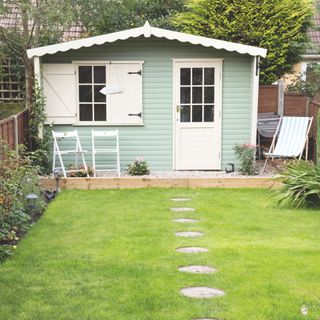 Garden laid to lawn with stepping stones leading to a blue/green garden shed