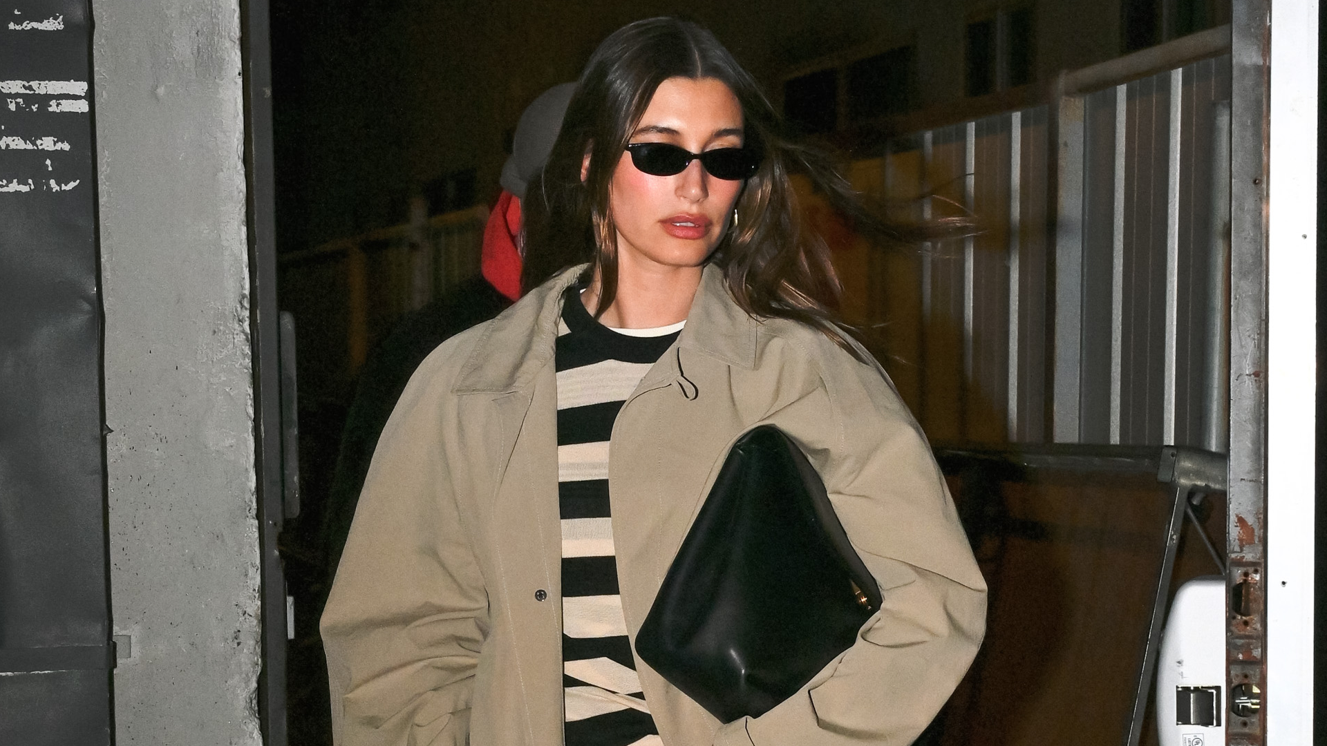 Hailey Bieber is spotted in NYC wearing a trench coat and an oversized clutch.