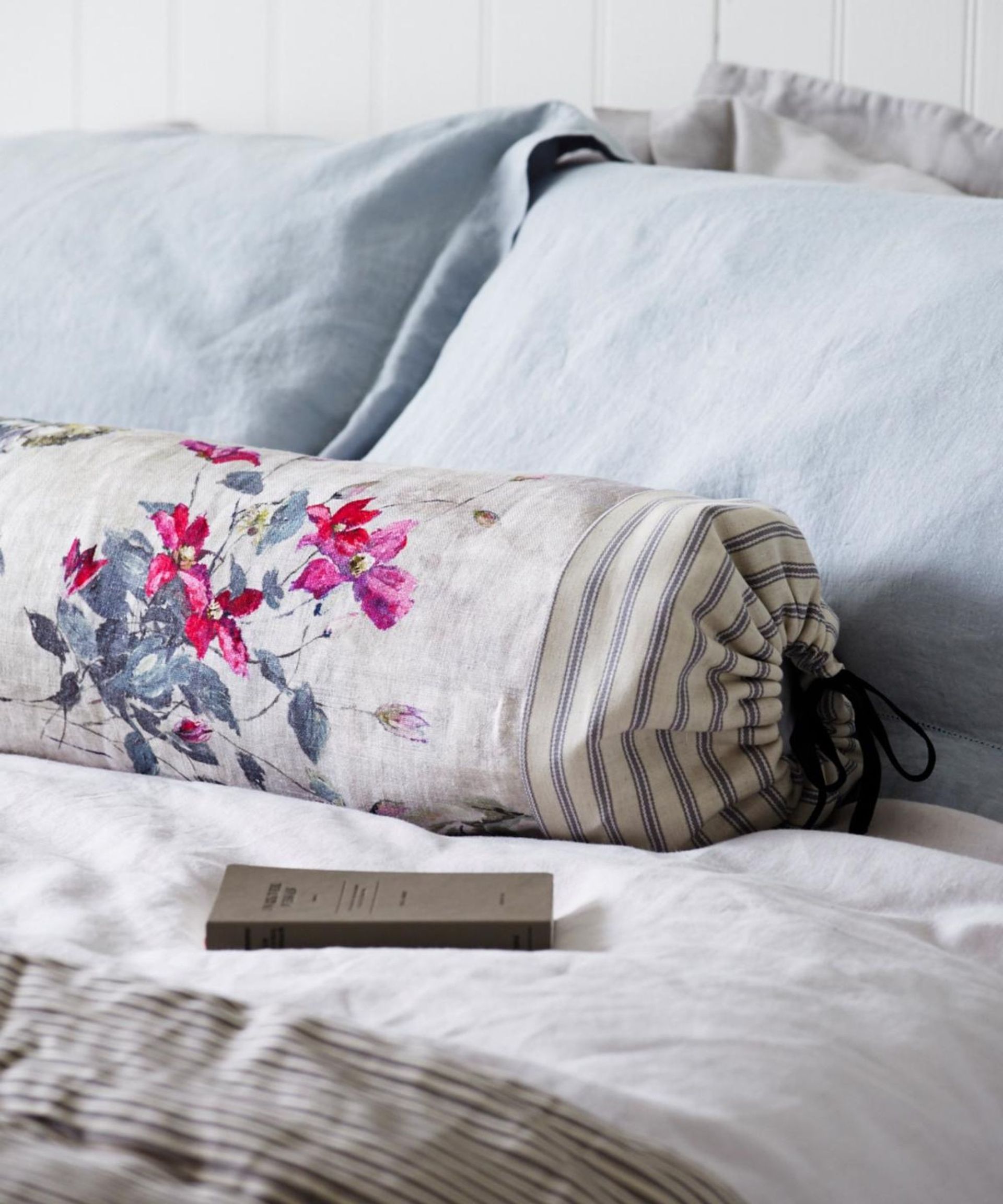 Blue and gray floral pillows on a bed.