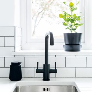 Sink with black taps and white metro tiled splashback