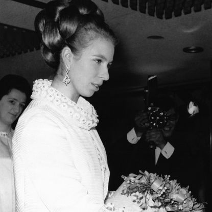 Princess Anne wearing a white coat holding flowers