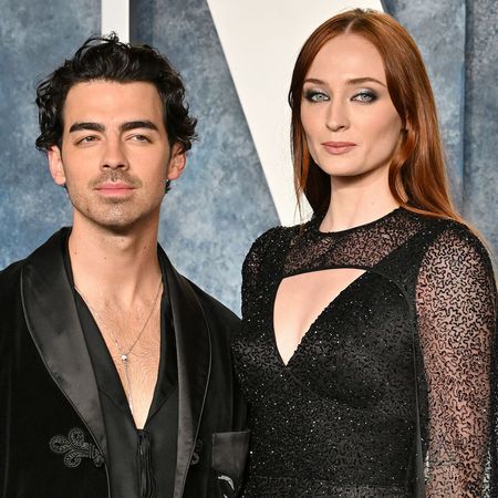 Joe Jonas wearing a black suit jacket and Sophie Turner in a black gown with a cutout neckline on the red carpet for the 2023 Vanity Fair Oscar Party