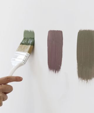 Someone painting strips of paint samples on a wall